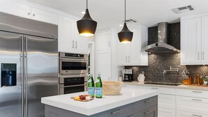 Una cocina moderna con electrodomésticos de acero inoxidable, armarios blancos y encimera de mármol.