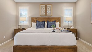 Un dormitorio con una cama grande, dos mesitas de noche, un cabecero de madera y dos apliques de pared.