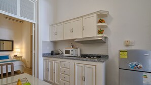Eine kleine Küche mit weißen Schränken, einer Mikrowelle, einem Kühlschrank und einer Essecke mit Tisch und Stühlen.