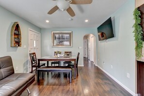 A dining area with a wooden table, chairs, and a ceiling fan.