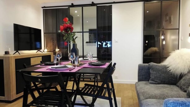 Uma sala de estar moderna com área de jantar, um sofá e uma televisão.