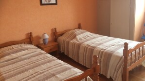 Une chambre à coucher avec deux lits en bois, une table de chevet avec une lampe et un tableau encadré au mur.