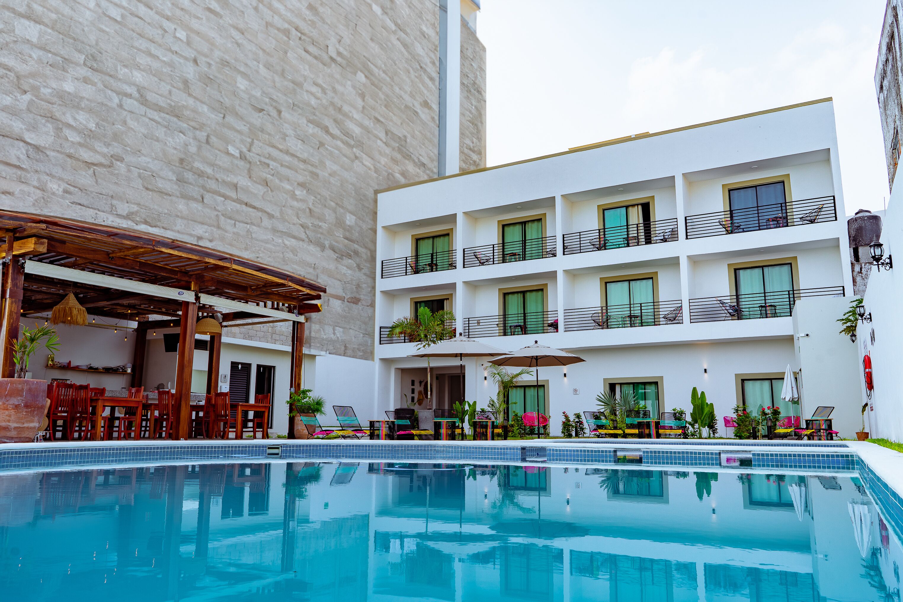 Un hotel con piscina, area relax all'aperto e un edificio a più piani con balconi.
