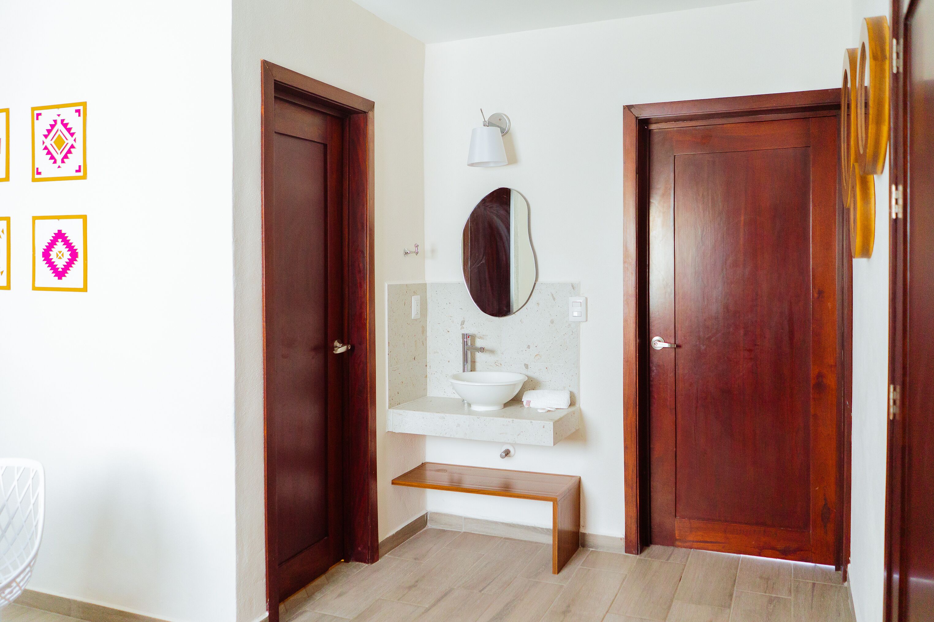 Une salle de bain avec une porte en bois, un lavabo blanc, un miroir et un porte-serviettes.