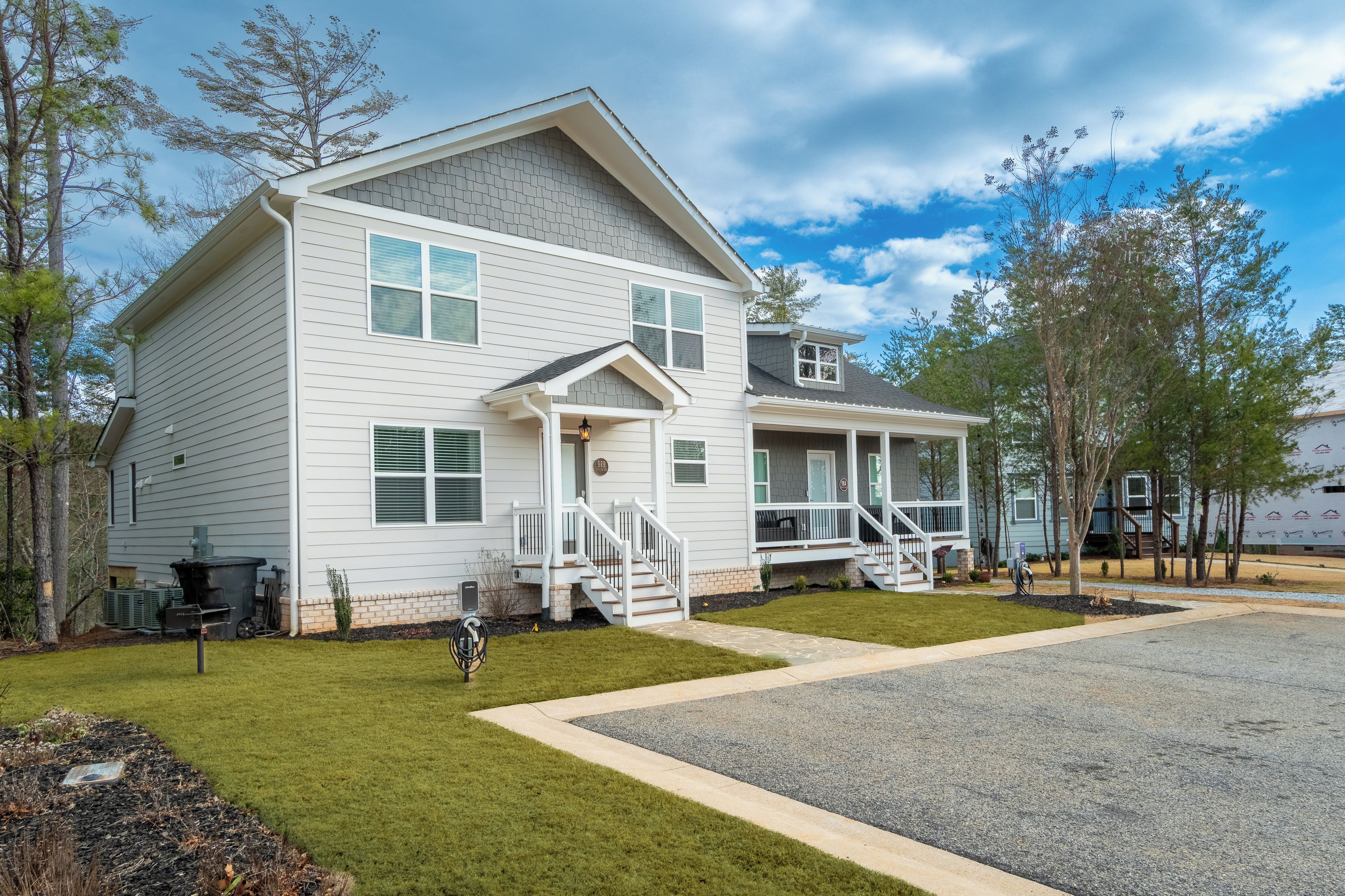A two-story residential building with a front porch, a garage, and a well-maintained lawn.
