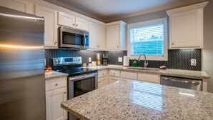 A modern kitchen with white cabinets, stainless steel appliances, and a granite countertop.