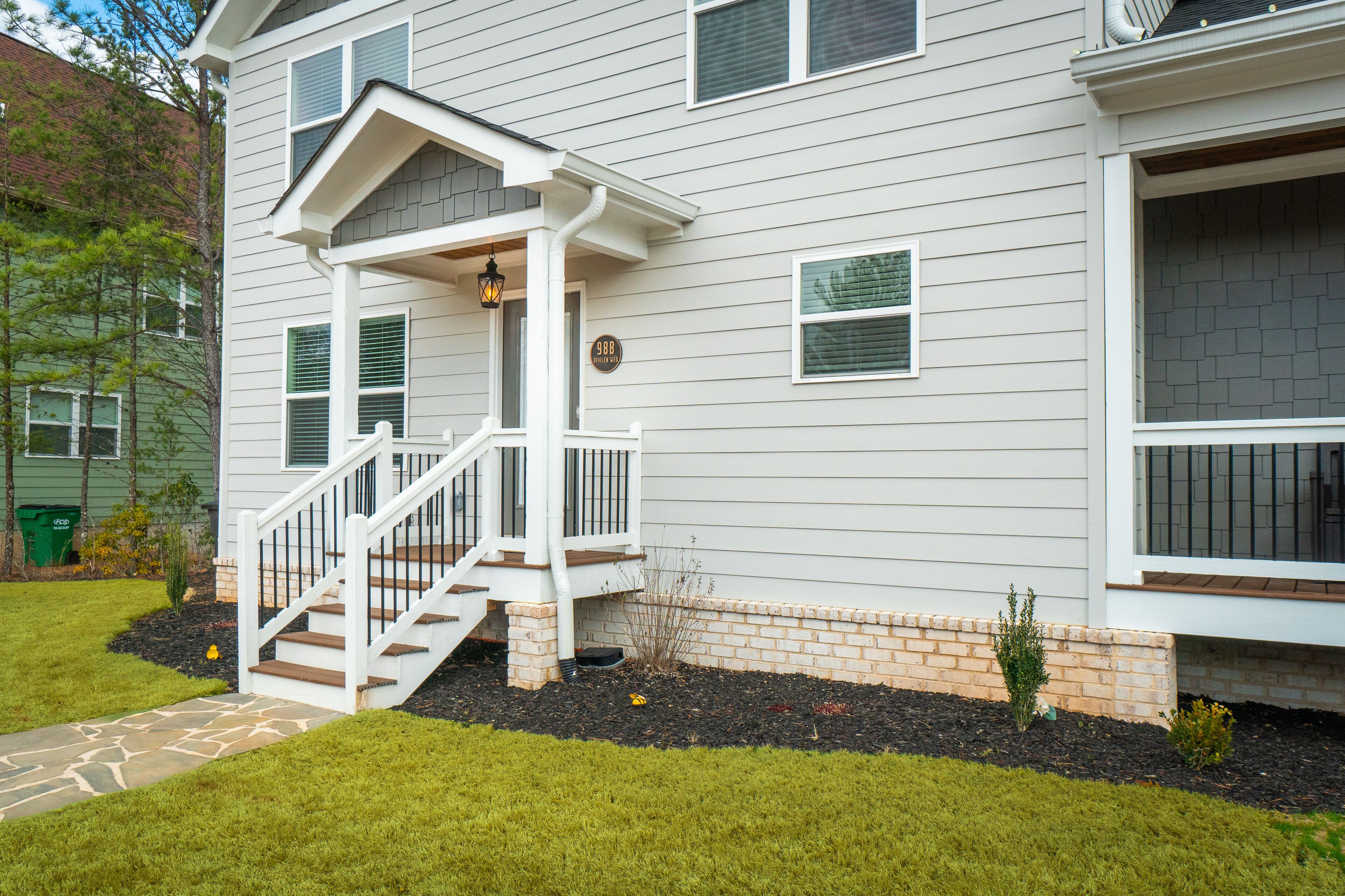 A two-story house with a front porch, a staircase, and a brick foundation.