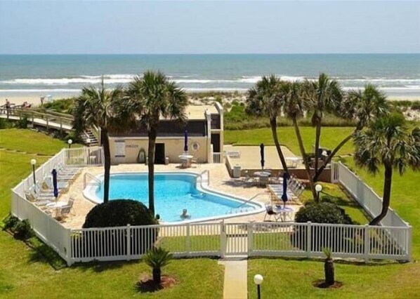Relax by the ocean-view pool surrounded by palm trees and lounge chairs.