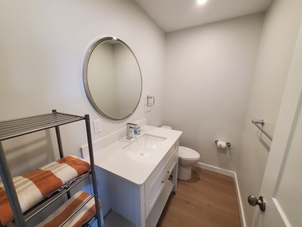 Une salle de bain avec un lavabo blanc, des toilettes, un miroir rond et un porte-serviettes avec des serviettes.