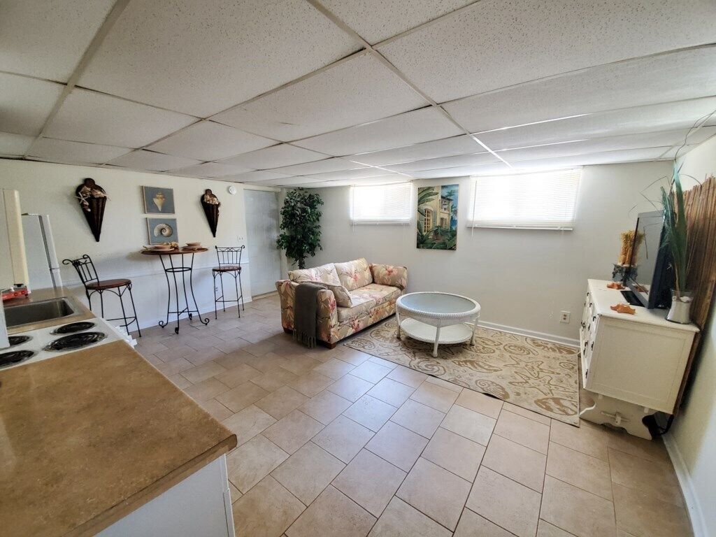 A spacious living area with a sofa, chairs, a small round table, a kitchen area with a stove, and a dining table.