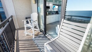 Ein Balkon mit weißem Stuhl, einem kleinen Tisch und Blick aufs Meer.