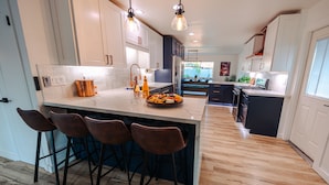 A modern kitchen with a central island, bar stools, and pendant lighting. - Four Palms - Pool BBQ Fire Pit - 5 min to Old Town (Scottsdale)