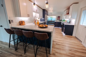 Una cocina moderna con una isla central, taburetes de bar e iluminación colgante.