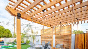 A wooden pergola with a swing bed, outdoor seating, and a fire pit. - Four Palms - Pool BBQ Fire Pit - 5 min to Old Town (Scottsdale)