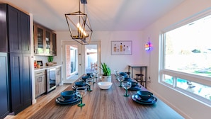 A modern kitchen with a long island, dark wooden cabinets, and a large window providing a view of the outdoors. - Four Palms - Pool BBQ Fire Pit - 5 min to Old Town (Scottsdale)