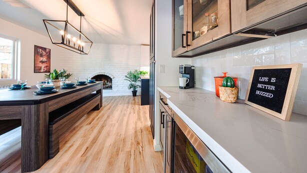 A modern kitchen with wooden flooring, a central island, and a built-in oven. There are cabinets with glass doors and a coffee machine on the counter. - Four Palms - Pool BBQ Fire Pit - 5 min to Old Town (Scottsdale)