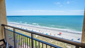 A balcony with a view of a beach with umbrellas and people. - New at Caravelle Resort - Pools - Honeymoon Suite! (Myrtle Beach)