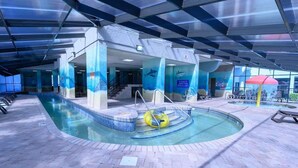 En inomhuspool med en central, cirkelformad del och en mindre, rektangulär pool. Det finns trappsteg som leder ner i poolen, och en gul uppblåsbar badring syns.