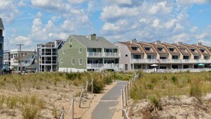 Fileira de apartamentos à beira-mar com um caminho de areia que leva à entrada.