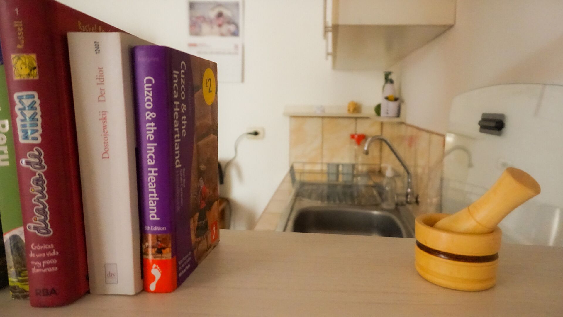 Una encimera de cocina con un mortero y pilón de madera, un lavamanos y un salpicadero de azulejos.