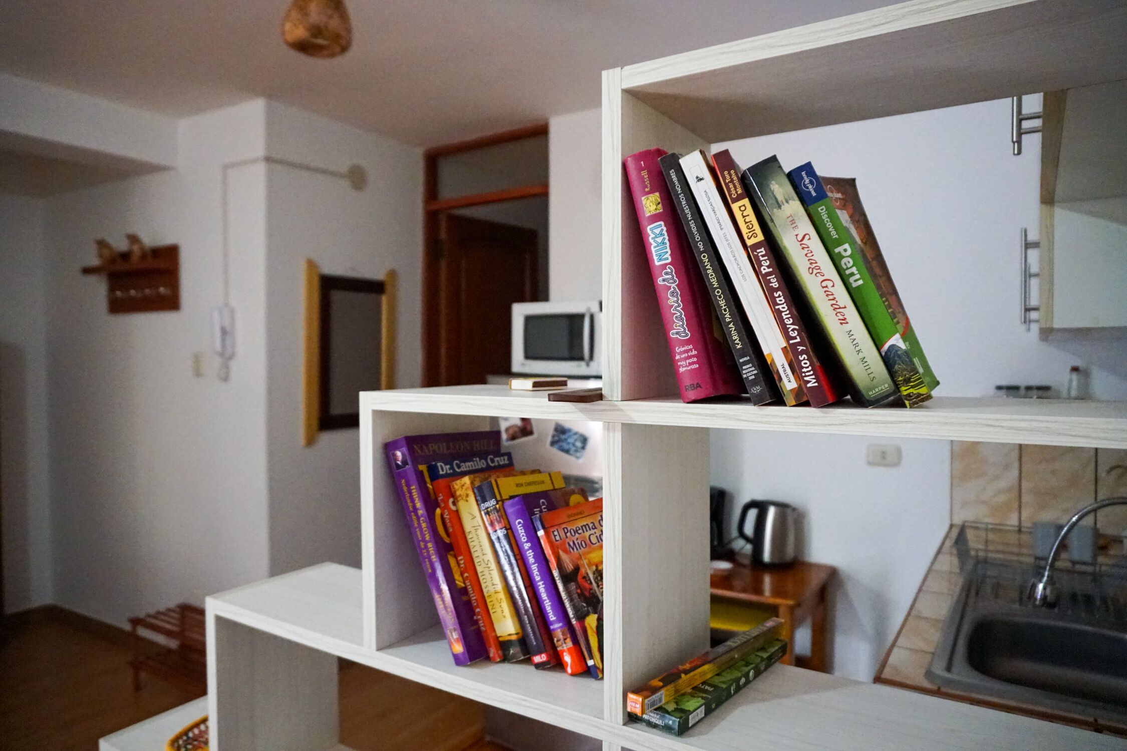A room with a white bookshelf containing books and a small television on a shelf.