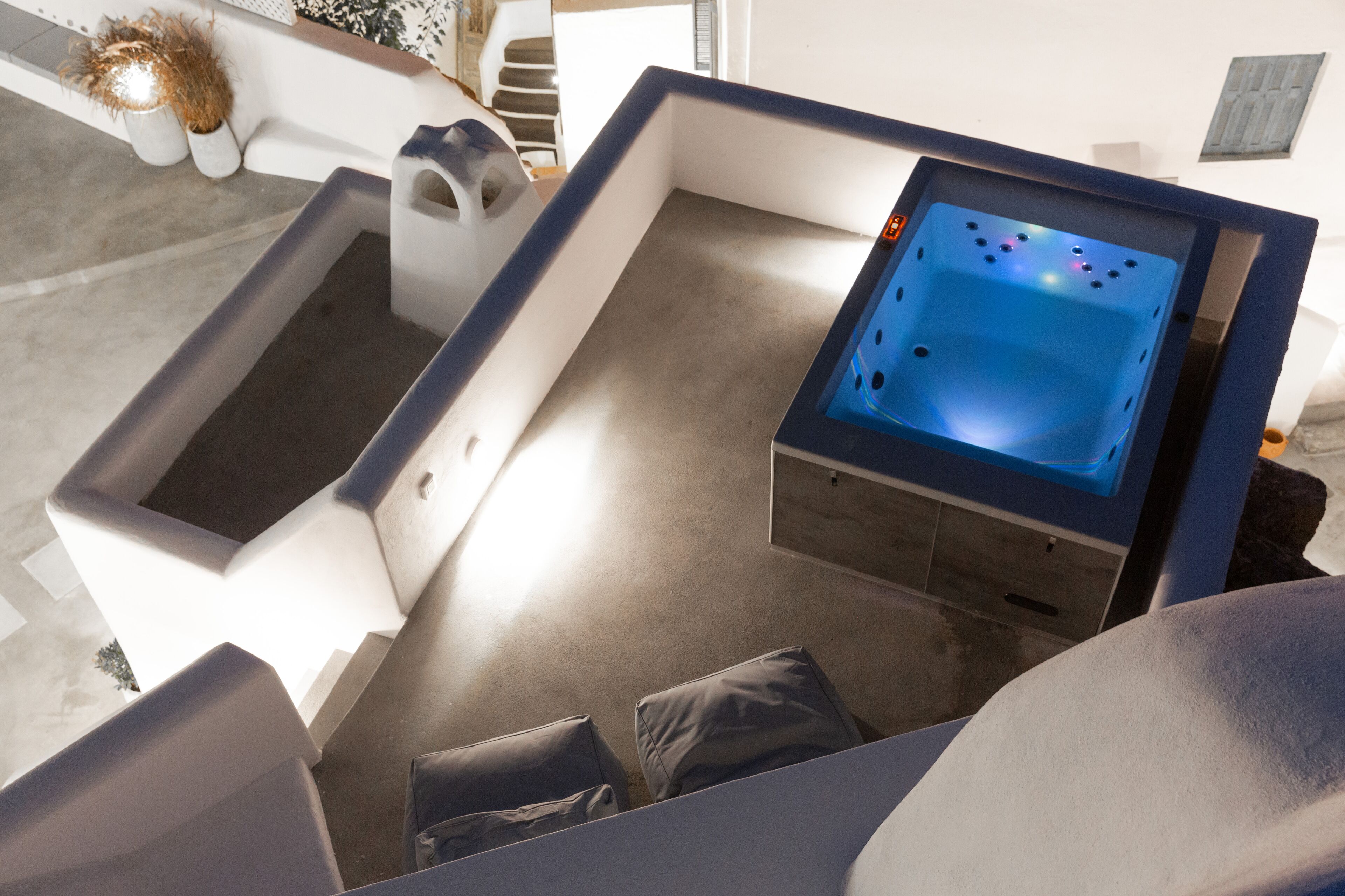 A modern outdoor hot tub area with a built-in seating area and a small table.