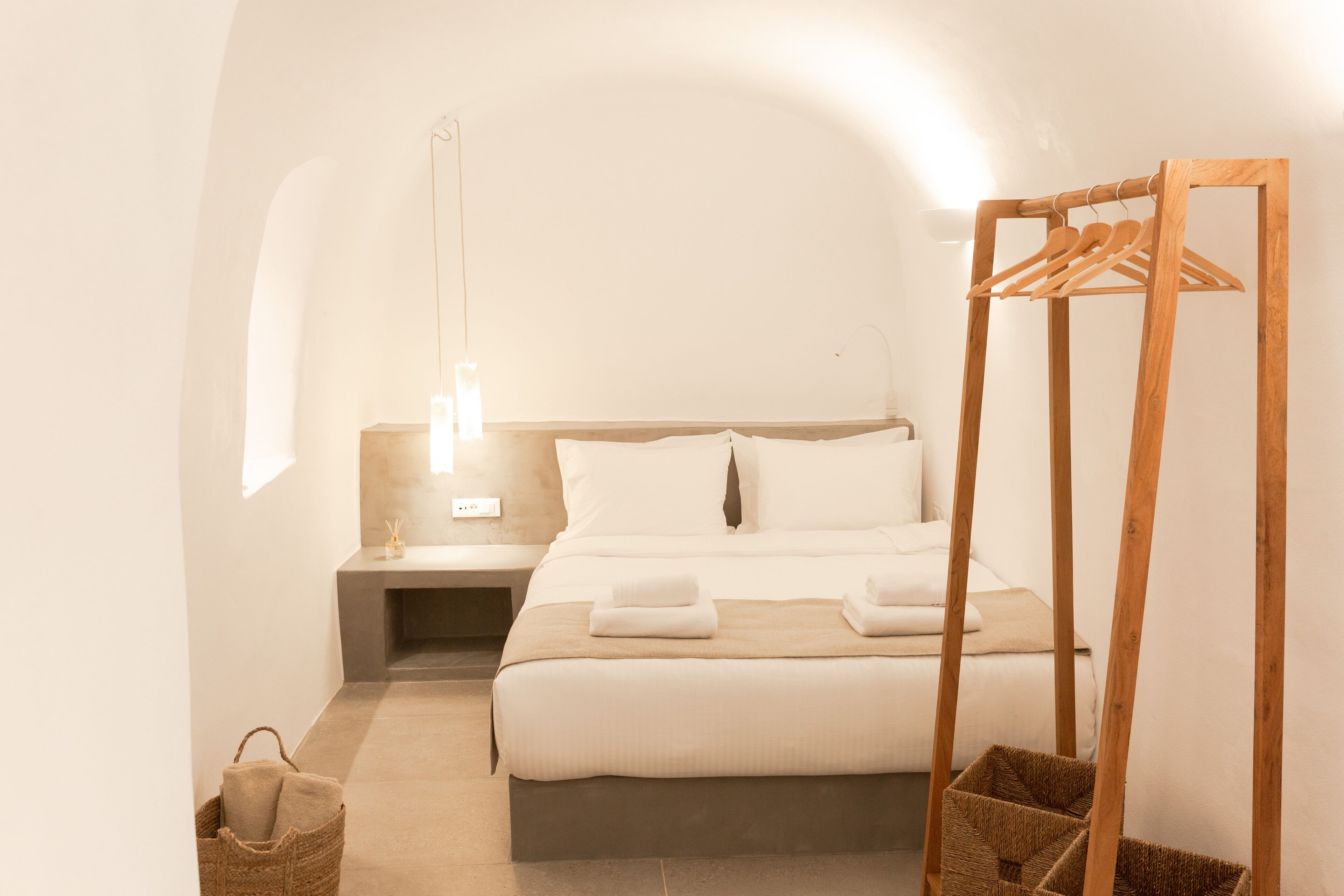 A bedroom with a bed, bedside table, hanging clothes rack, and a small basket.