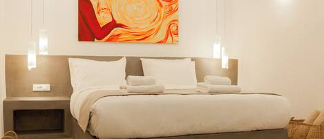 A modern hotel room with a large bed, bedside tables, a wall-mounted painting, and a basket on the floor.