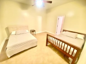 Une chambre avec deux lits, une petite table et une porte.