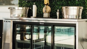 A modern kitchen with a flat-screen TV mounted above a green wall, a stainless steel cabinet below, and a decorative figure in the center. - * Beautiful Lakehouse with Pool and Movie Theater* (Casselberry)
