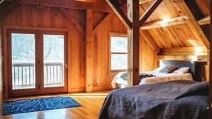 A wooden cabin room with a bed, a window, and a door.