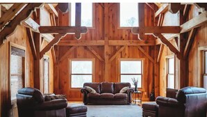 A spacious room with wooden beams, a large window, and a leather sofa.