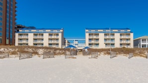 Ett hotell vid stranden med flera balkonger, en sandstrand precis utanför och en klarblå himmel.