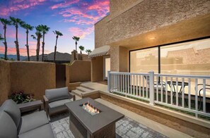 Relax on the patio with a sofa and table, surrounded by a fire feature and overlooking a dining area.