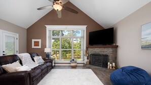 A cozy living room with a fireplace, a large window, and a ceiling fan. - 4BD 3BTH, Lakeview, huge covered outdoor patio Firepit, and Fishing @ Jolie Vue (Many)