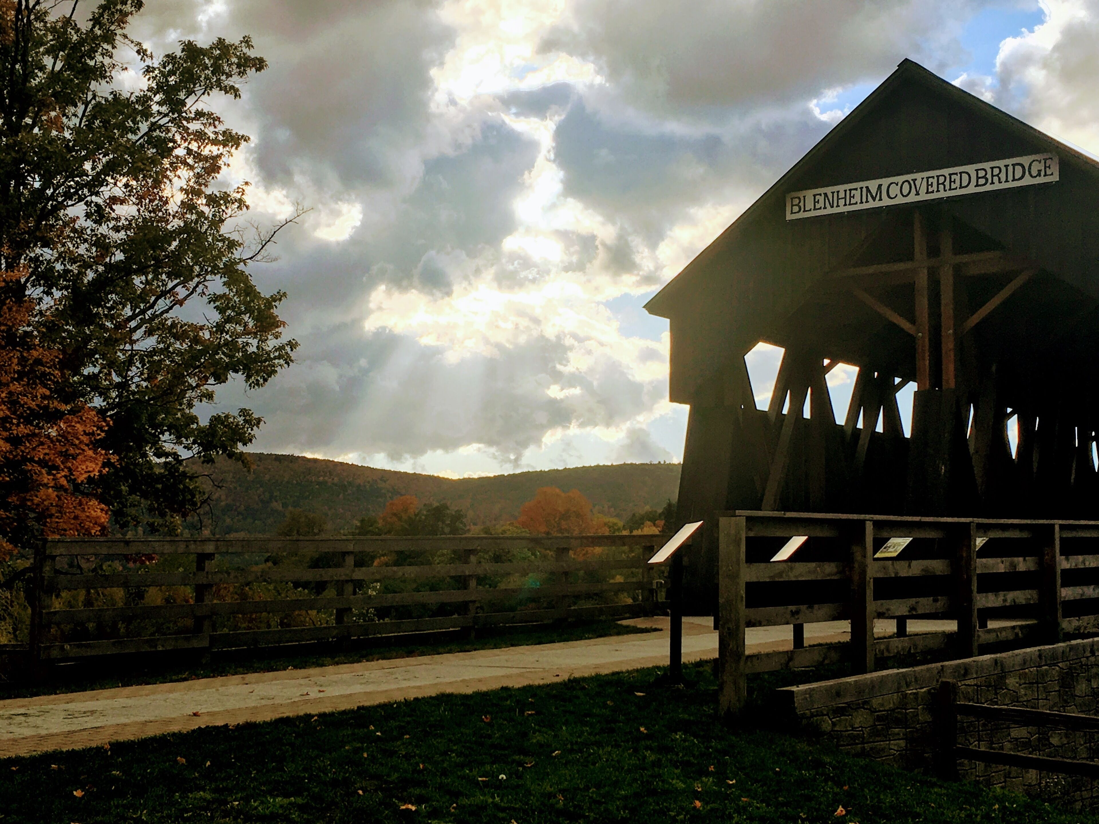 A covered bridge with a sign reading "BLEHEIM COVERED BRIDGE" and a wooden structure with a roof.