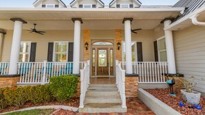 A two-story house with a covered porch, white railings, and a central staircase.