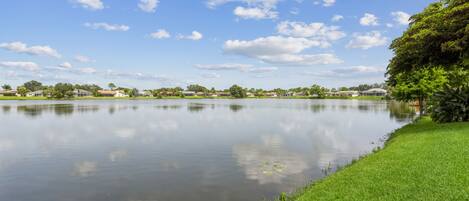 Ein ruhiger See mit einer grasbewachsenen Uferbank und blauem Himmel.