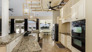 A spacious kitchen with granite countertops, white cabinetry, and stainless steel appliances.