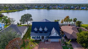 A large house with a blue roof, a covered porch, and a view of a lake.