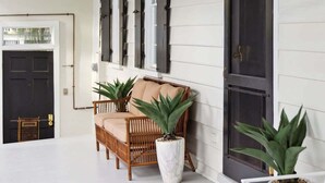 A covered porch with a white exterior, a wooden bench, and potted plants. - Private Pool & Historic Home-‘The Walled Garden’ (Charleston)