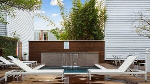 A pool area with lounge chairs, a waterfall feature, and a brick wall. - Private Pool & Historic Home-‘The Walled Garden’ (Charleston)