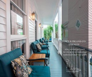 A traditional Charleston porch with teal sofas and wooden tables, offering a view of the greenery beyond. - Historic Boutique Home ‘The Bermuda’ (Charleston)