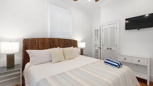 Ein Schlafzimmer mit Bett, Nachttischlampen, Deckenventilator, Fernseher und Kleiderschrank.
