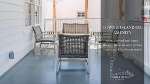 Un porche tradicional en Charleston con muebles de mimbre, palmeras y vistas de la ciudad.