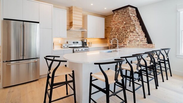 Una cocina moderna con una isla central, electrodomésticos de acero inoxidable y una chimenea de ladrillo.