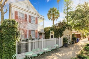A white house with pink shutters, a white picket fence, and green outdoor seating. - Private Pool & Historic Home - ‘Sugarsweet House’ (Charleston)