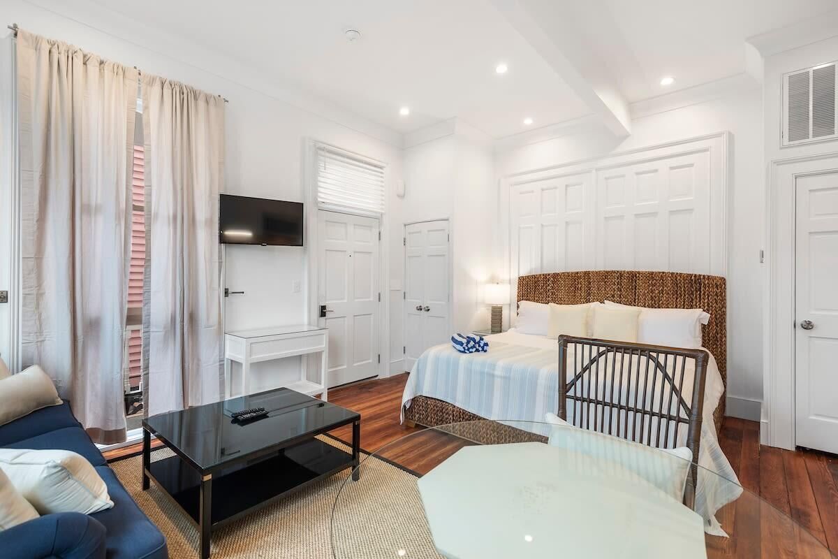 A hotel room with a bed, a TV mounted on the wall, a desk, and a sofa.