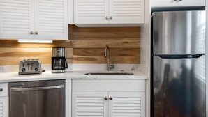 A modern kitchen with white cabinets, stainless steel appliances, and a wooden backsplash. - Boutique Historic Home ‘The Cisco’ (Charleston)