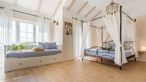 A bedroom with a four-poster bed, a daybed with storage drawers, and a large window with curtains. - Villa LEMON BELLISSIMA (Ljutići)